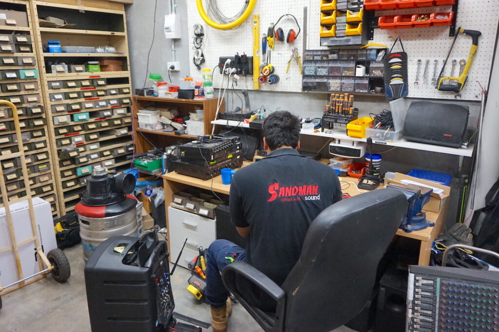 Sandman Sound technician working on an amplifier repair in workshop.