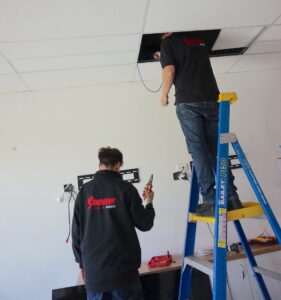 Sandman Sound technicians up a ladder investigating wiring fault in ceiling.