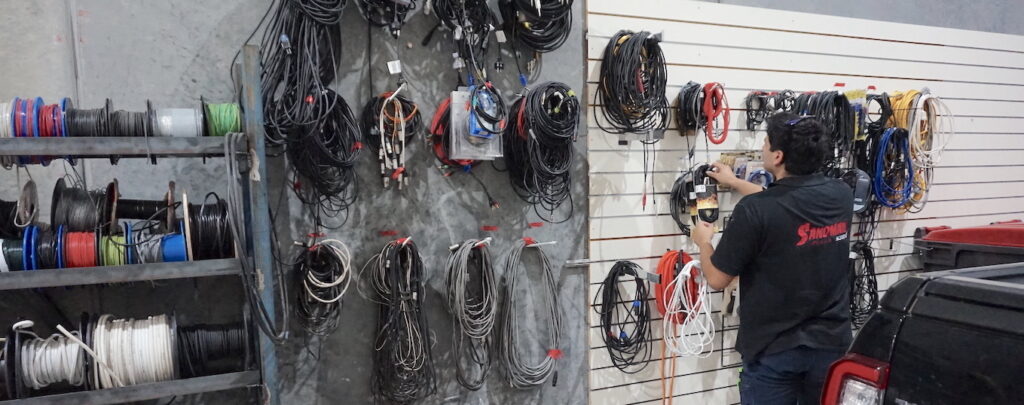 Sandman Sound - A Sound technician choosing a cable of a wrack of school speaker electrical equipment